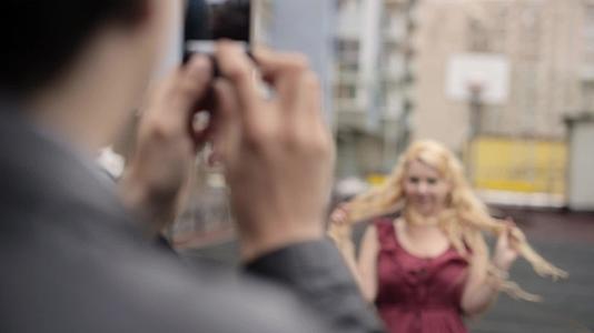 年轻男子用手机拍了一张女友在街上玩得开心的照片视频的预览图