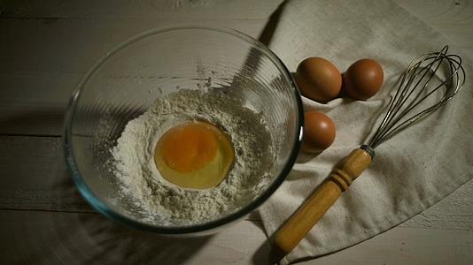 将鸡蛋浸泡在玻璃碗将生鸡蛋倒入面粉中烘烤视频的预览图