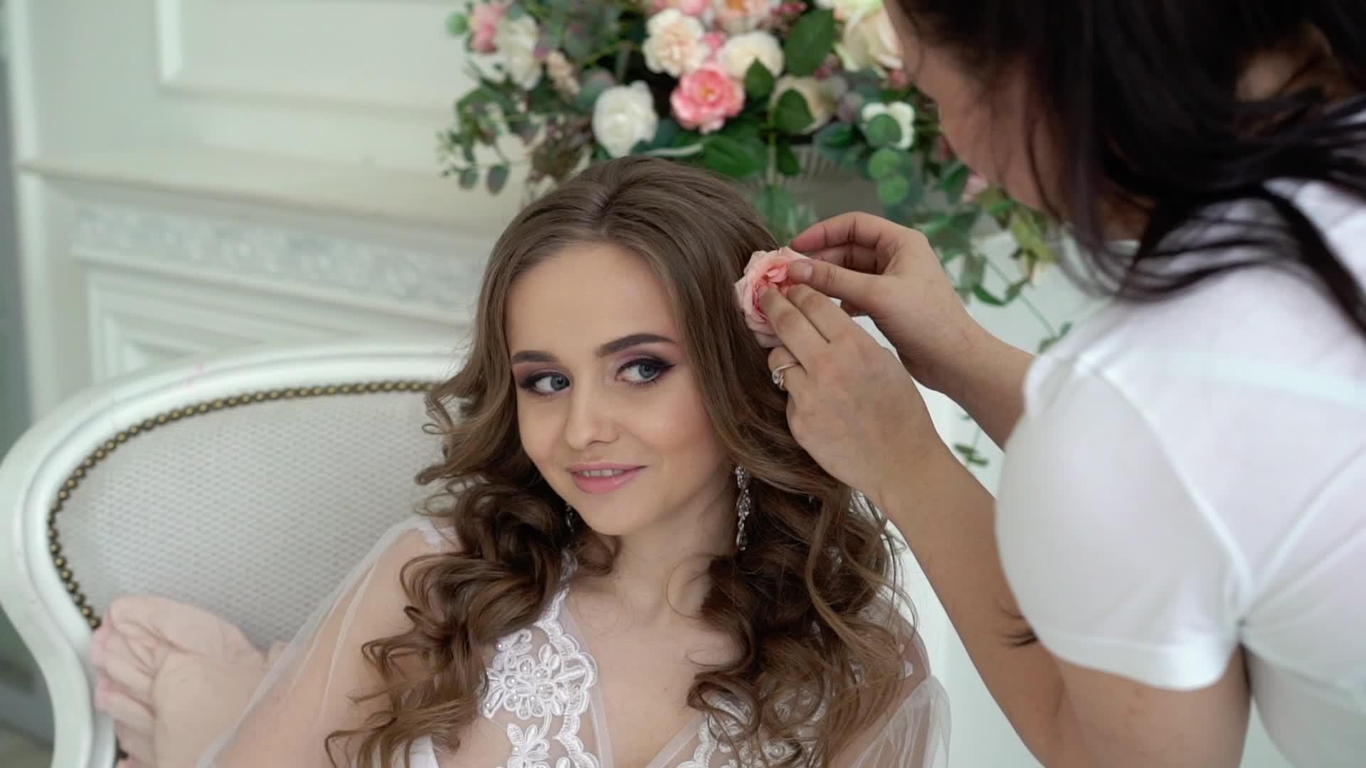 女人用鲜花染年轻漂亮新娘的头发穿白色内衣视频的预览图