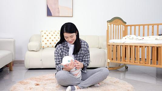 年轻妈妈坐在地毯上呵护宝宝视频的预览图