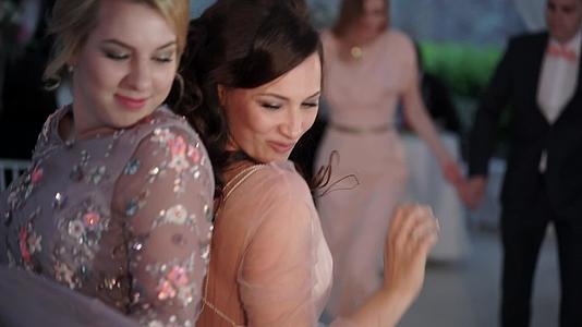 两个年轻女孩在聚会上跳舞朋友们穿着晚礼服参加婚礼视频的预览图