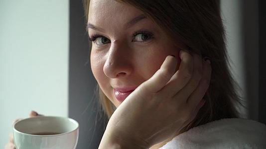清晨年轻漂亮的女孩在浴袍里喝咖啡视频的预览图