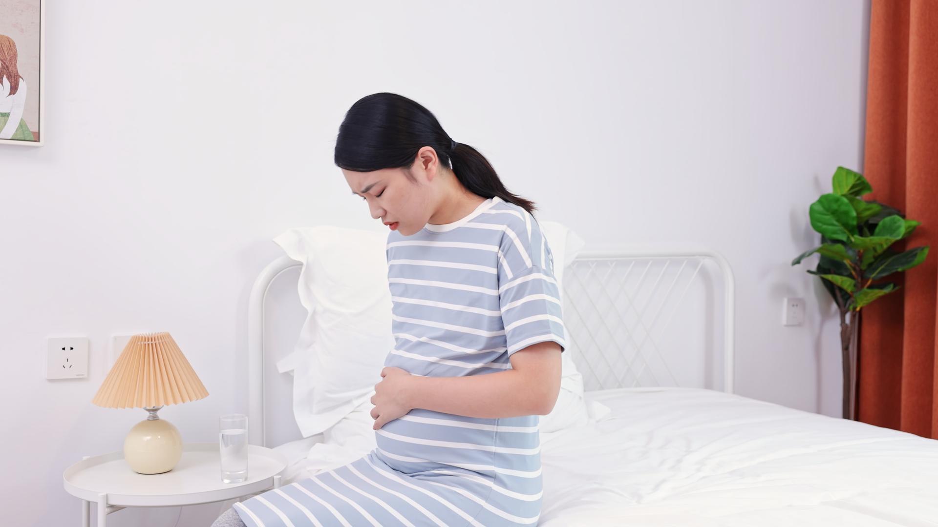 年轻孕妇坐在床上抚摸肚子视频的预览图