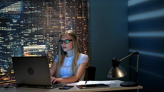 漂亮的女程序员晚上在现代办公室用电脑工作视频的预览图