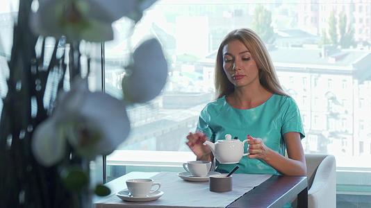 美丽的女人在喝茶在餐馆里等着有人吃早餐视频的预览图