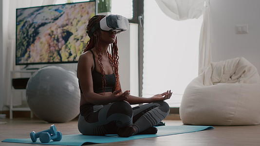 黑人教练女子坐在瑜伽地图上戴着虚拟现实头盔视频的预览图
