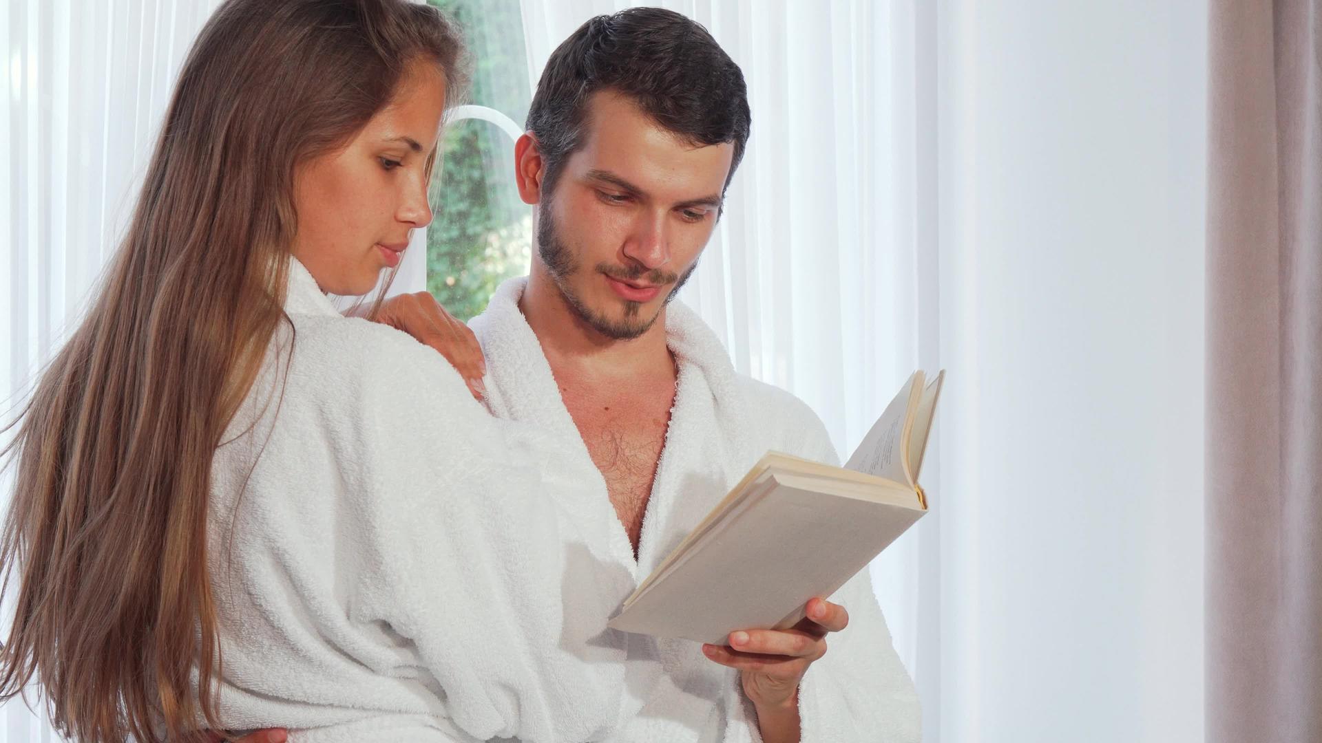 穿着浴袍的幸福情侣一起读一本书视频的预览图
