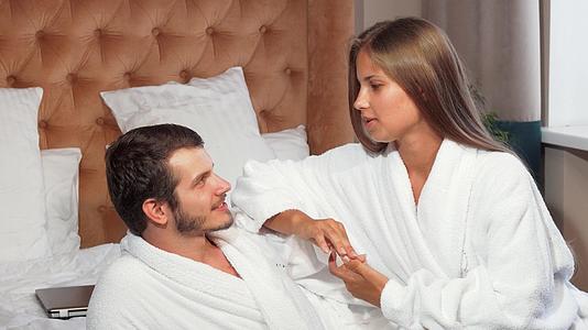一对漂亮的夫妇在床上放松穿着浴袍视频的预览图