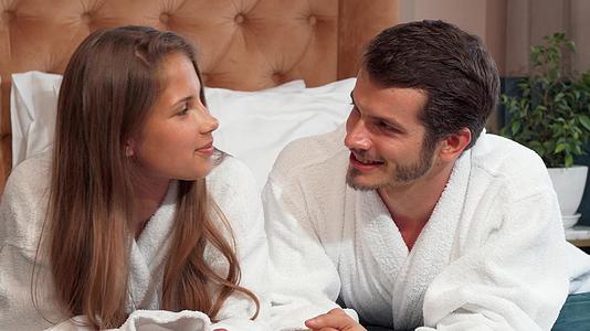 一对幸福的夫妇在床上聊天穿着浴袍躺在床上视频的预览图