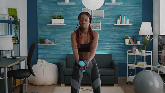 深色皮肤柔软的女性用哑铃蹲着锻炼视频的预览图