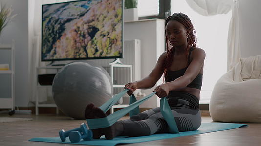 在运动服上穿黑色皮肤的运动员使用健身弹性锻炼视频的预览图