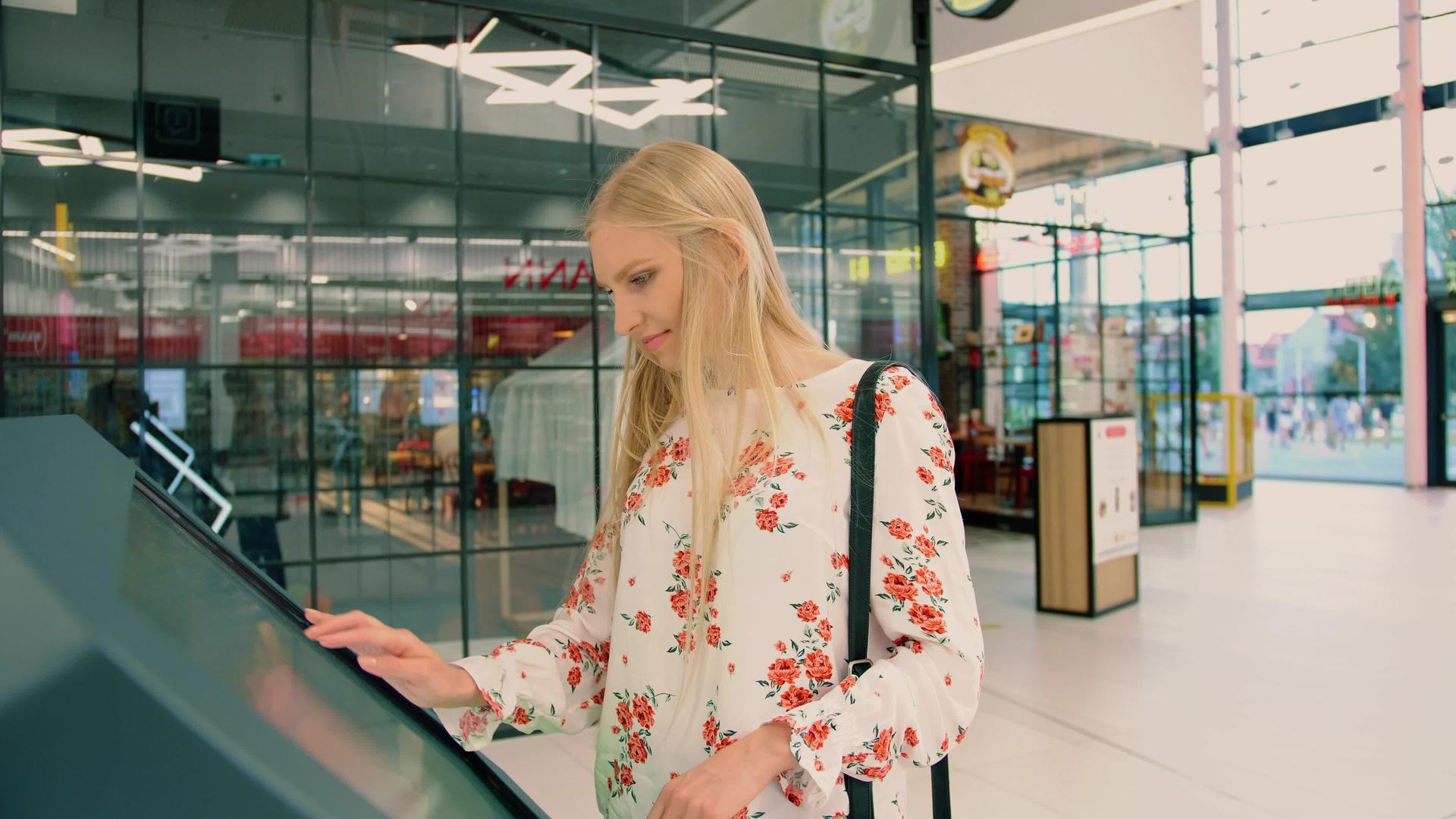 年轻女性在现代购物中心的导航板上寻找正确的方向视频的预览图