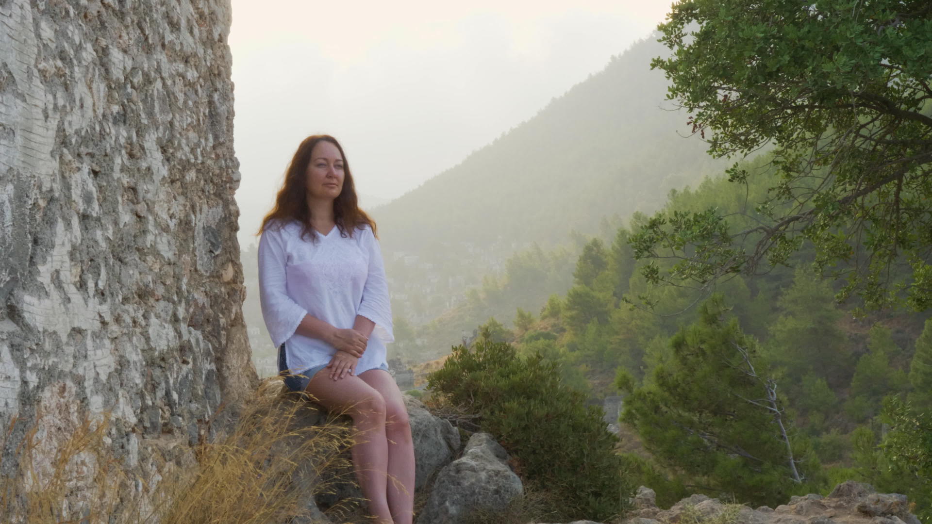 坐在石雾山上的无忧无虑的女人视频的预览图