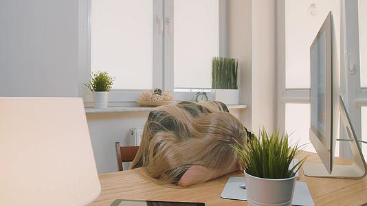 疲惫的金发女办公室工作人员穿着优雅的西装躺在桌子上放松视频的预览图