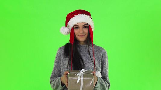 美丽的圣塔女孩微笑着拿着圣诞礼物给相机视频的预览图