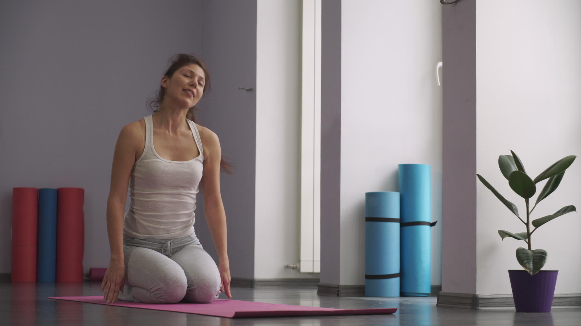 在健身房坐在垫子上放松锻炼的女性视频的预览图