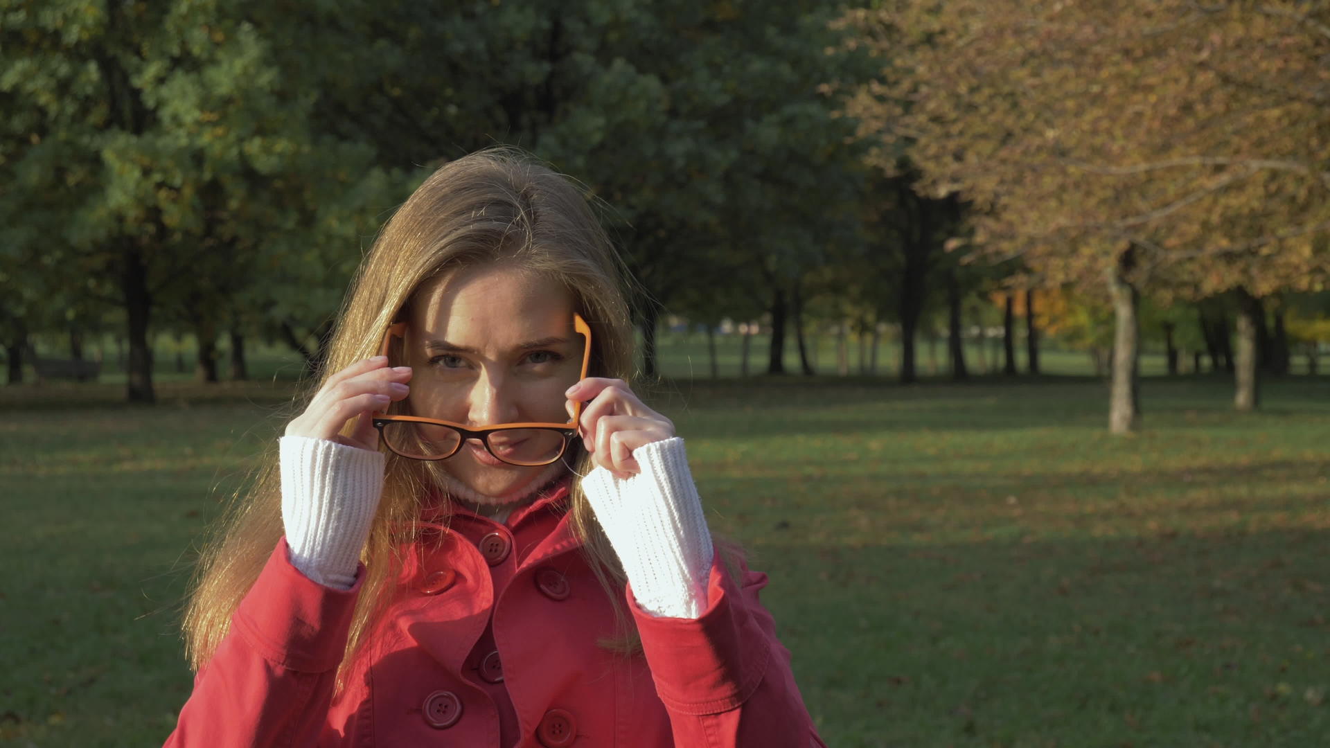 一位微笑的年轻女士在绿色公园戴眼镜镜头慢动作视频的预览图