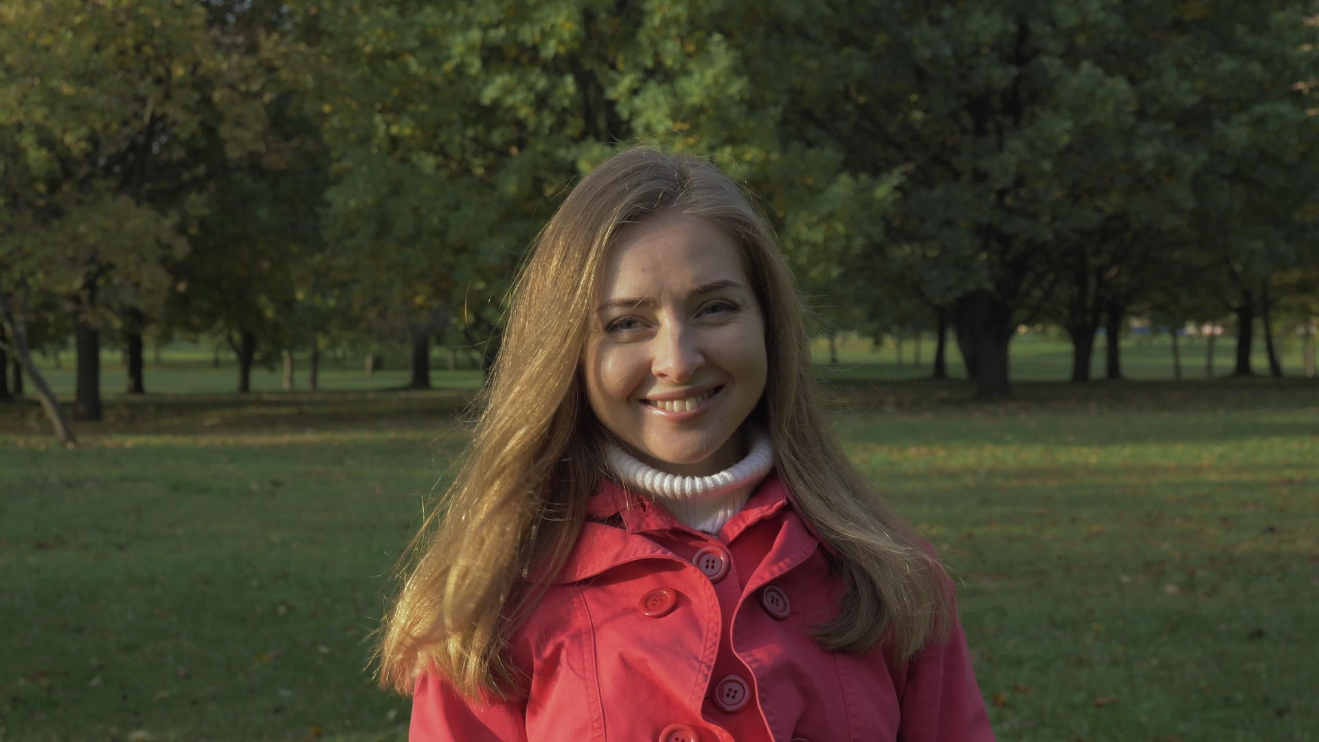 在绿色公园微笑和抚摸头发的肖像中年轻女子在镜头中慢动作视频的预览图