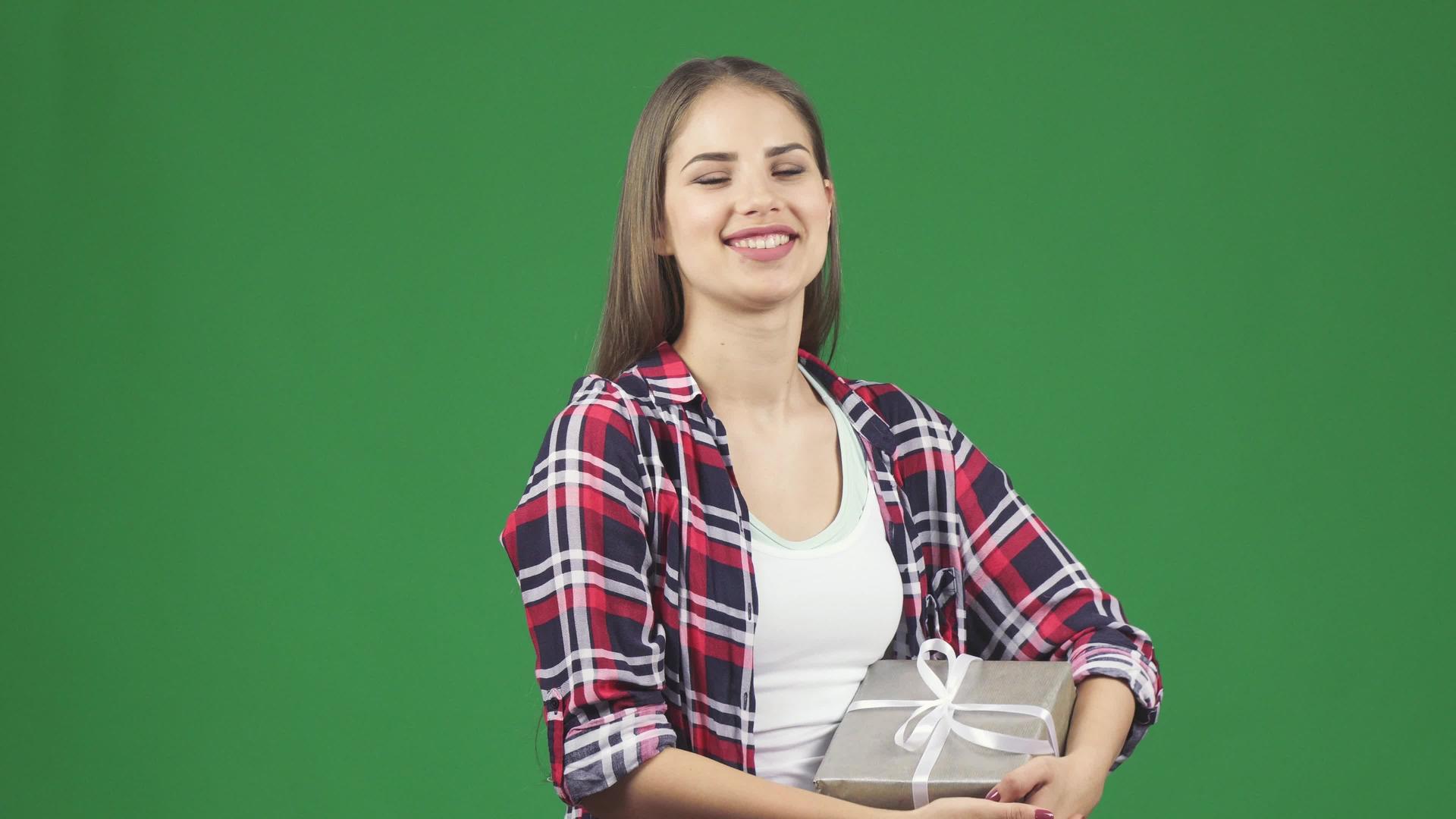 这位快乐、年轻、美丽的年轻女士微笑着向拿着礼物的相机挥手视频的预览图