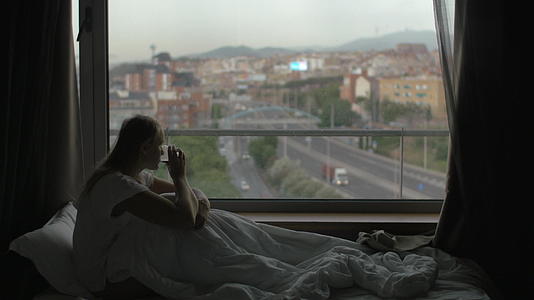 女人在床上喝茶看城市视频的预览图