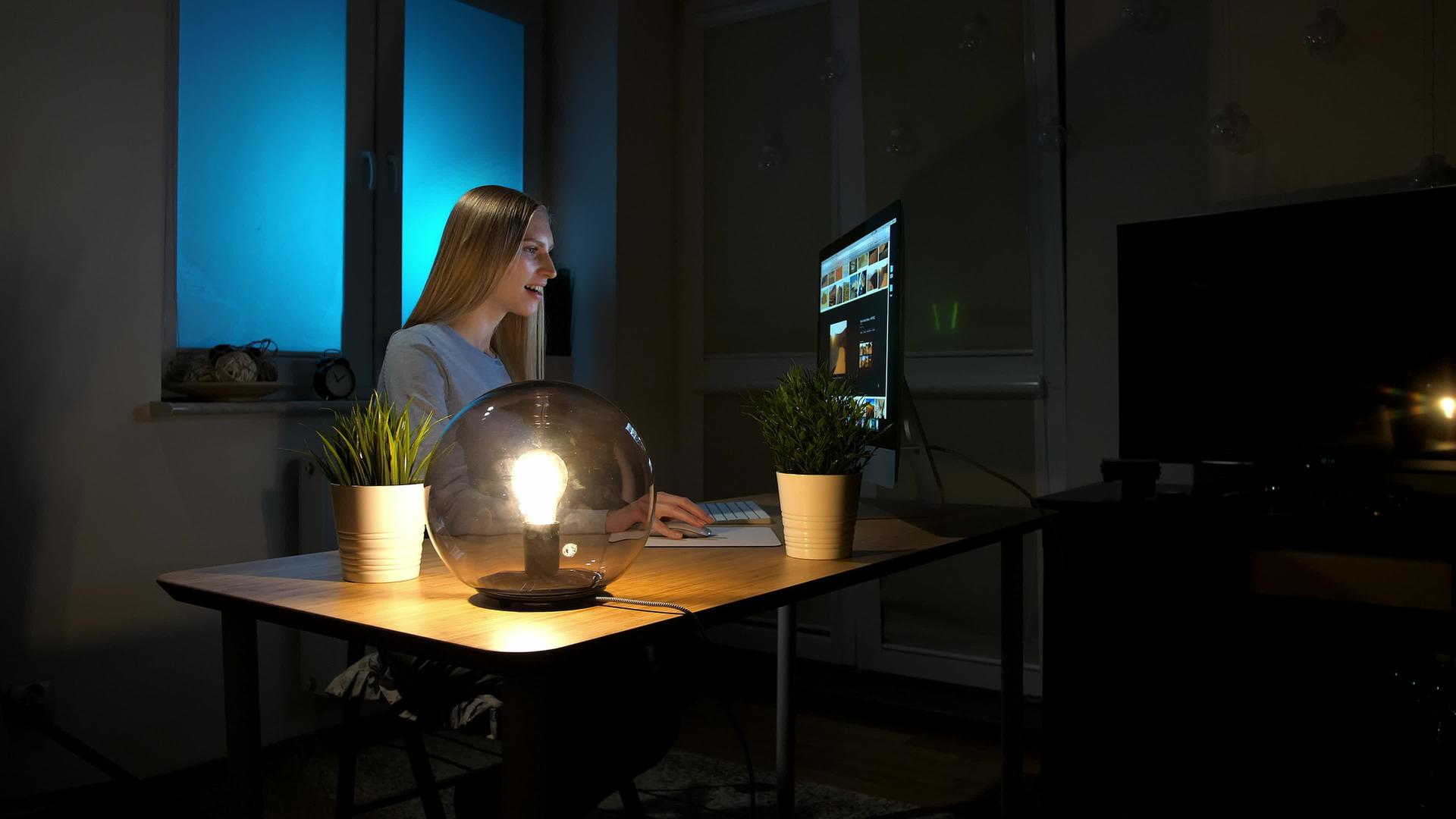 微笑的女人晚上在电脑上工作微笑的女人穿着格子衬衫坐在那里视频的预览图