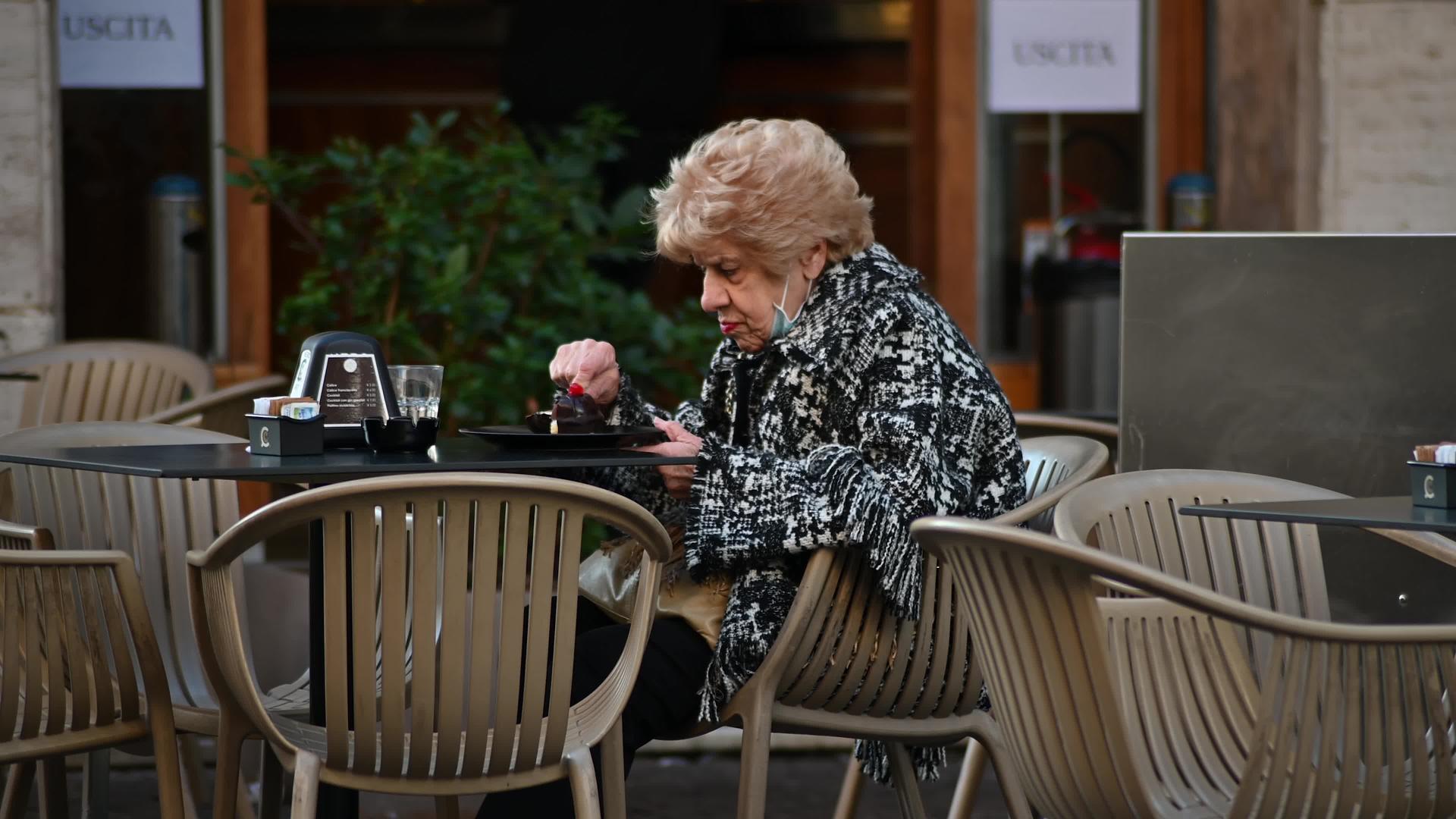 吃冰淇淋的女人坐在咖啡馆外面的桌子上视频的预览图