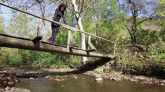 站在林中木桥上的悲惨徒步旅行妇女视频的预览图