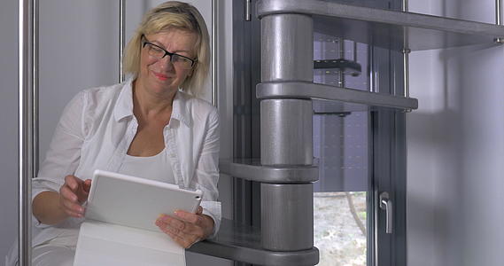 成年女性用平板电脑坐在楼梯上视频的预览图