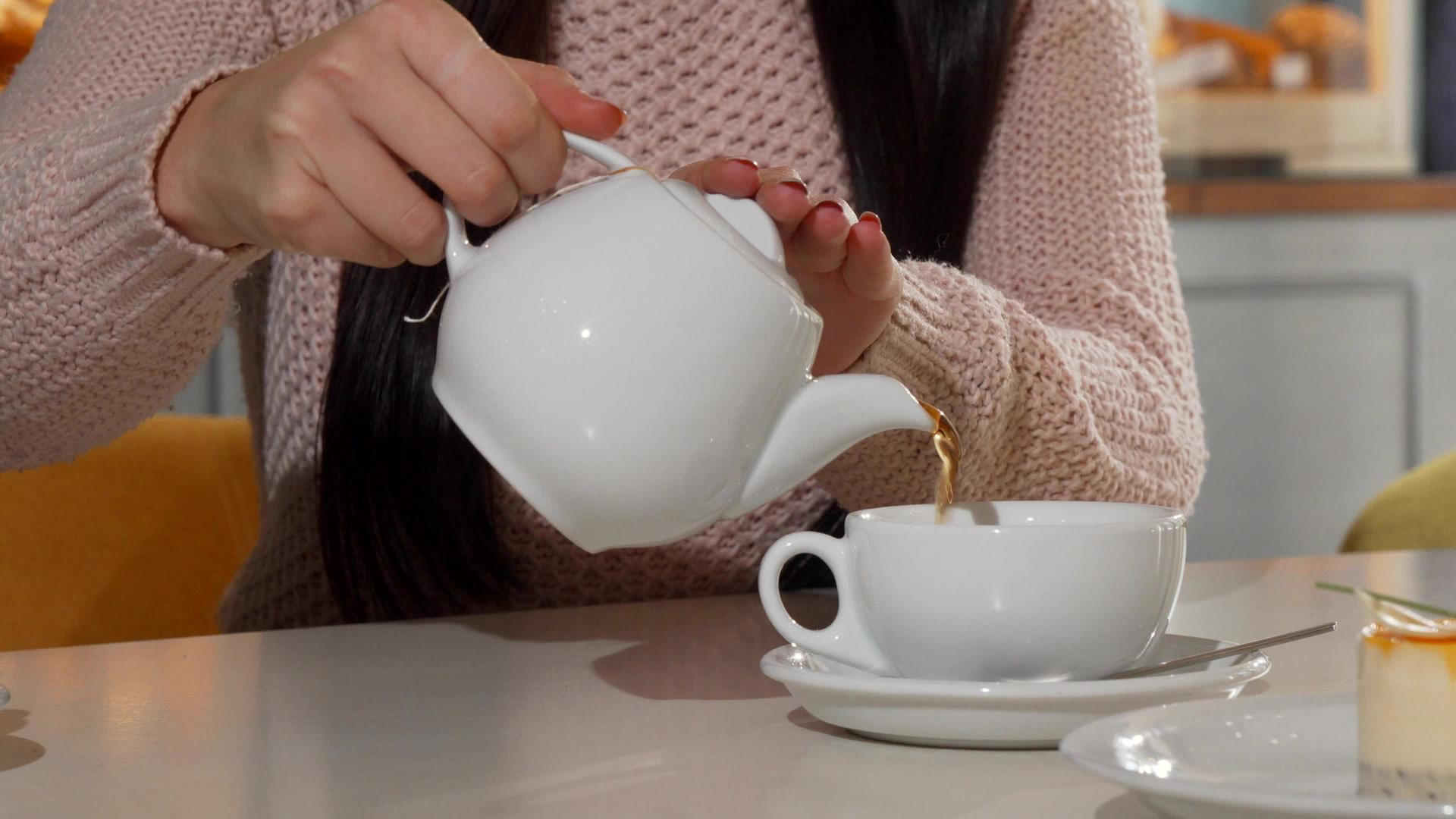 女人把茶倒进咖啡店的杯子里视频的预览图
