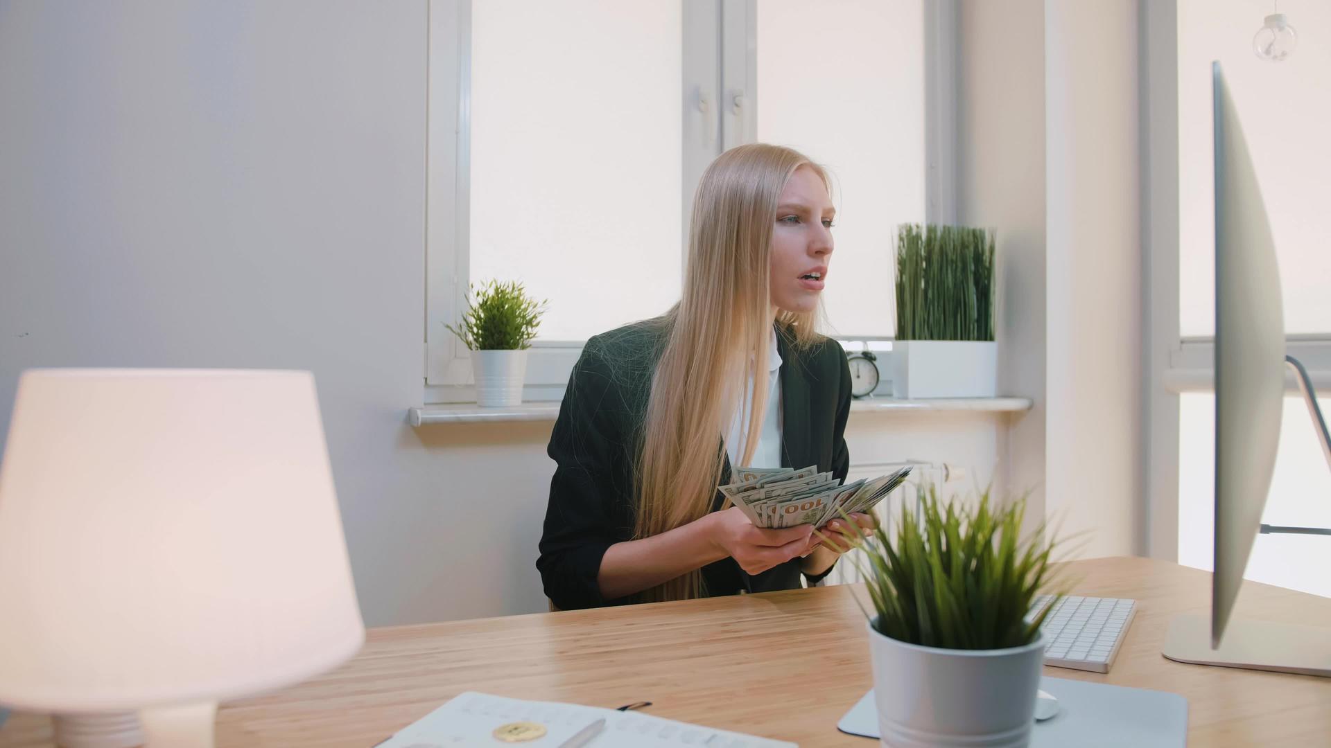 优雅的金发女性坐在工作场所的手中在办公室里庆祝成功的女性视频的预览图