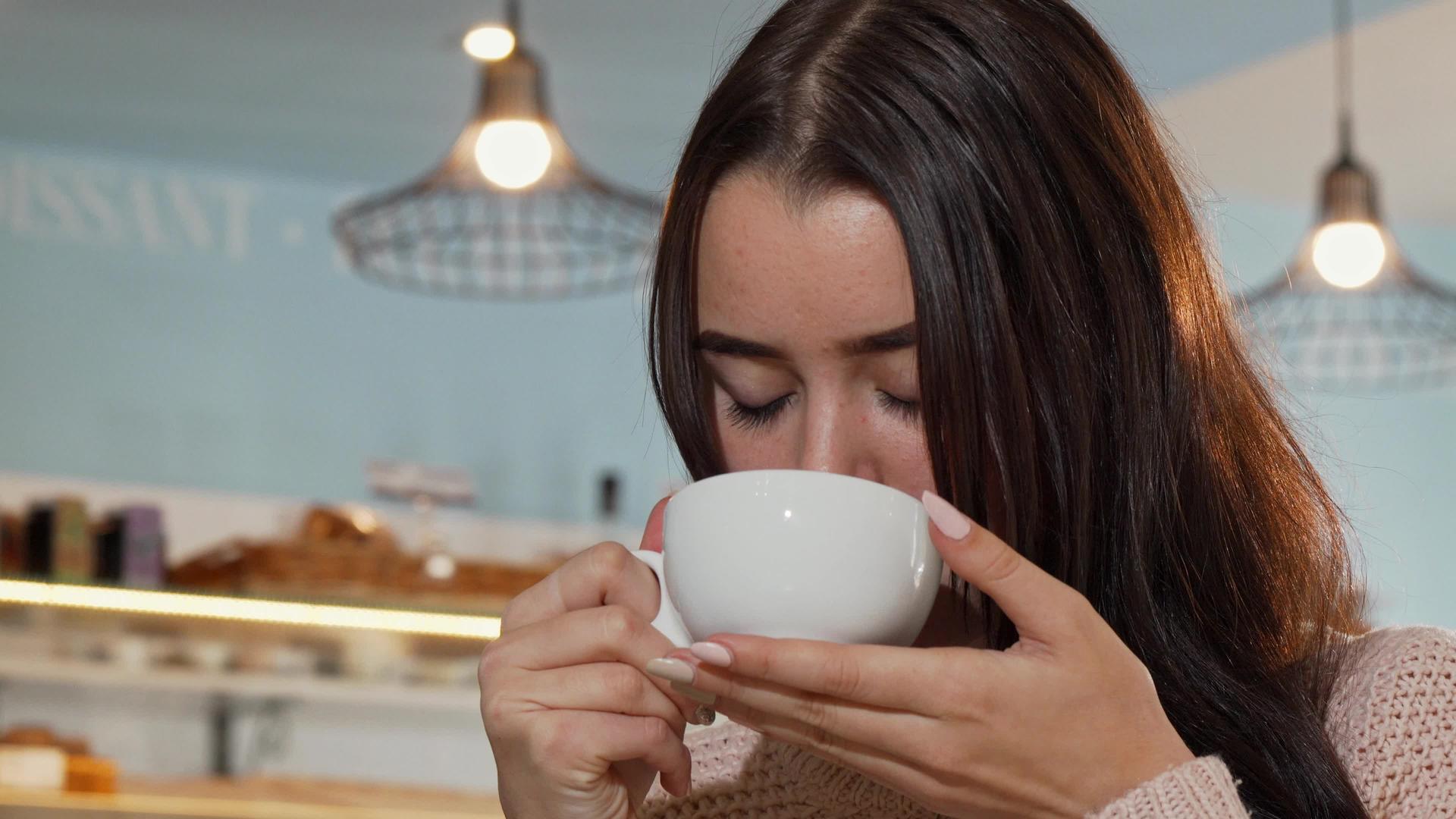 从低角度拍摄一个美丽的女人微笑着在镜头前拿着一杯咖啡视频的预览图