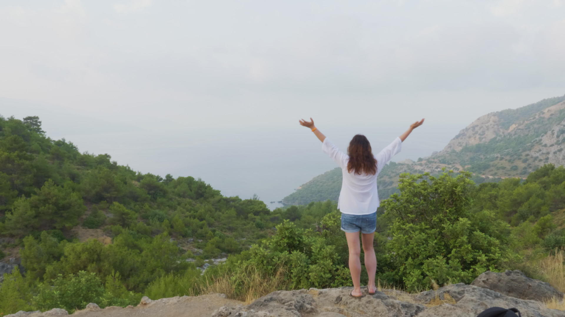 站在山顶上的年轻女子举起手视频的预览图