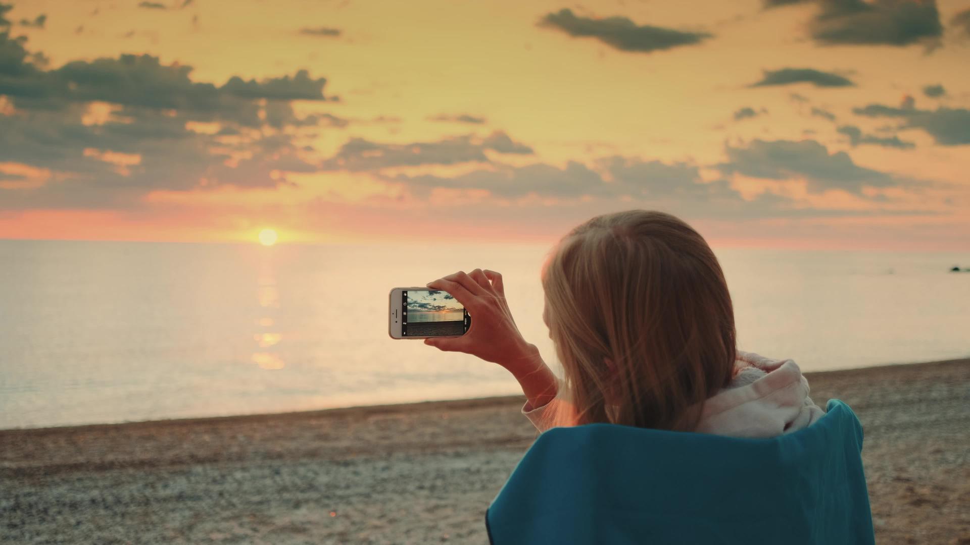 年轻女性拍摄日落视频智能手机视频的预览图