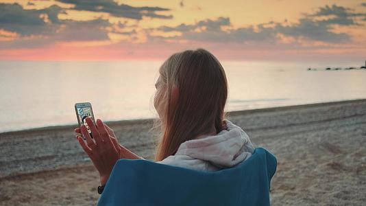 年轻女子在岸上用智能手机打视频电话视频的预览图
