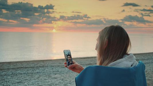 在海滩上用智能手机给朋友打视频电话视频的预览图