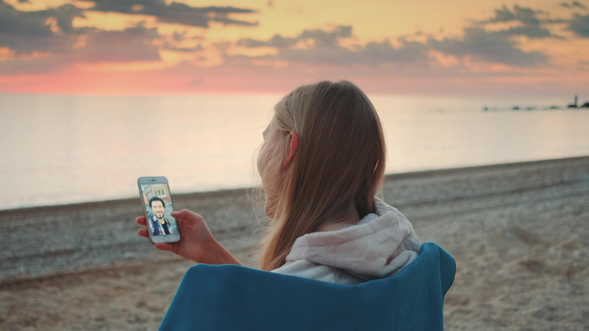 在岸上用智能手机打视频电话的女性视频的预览图