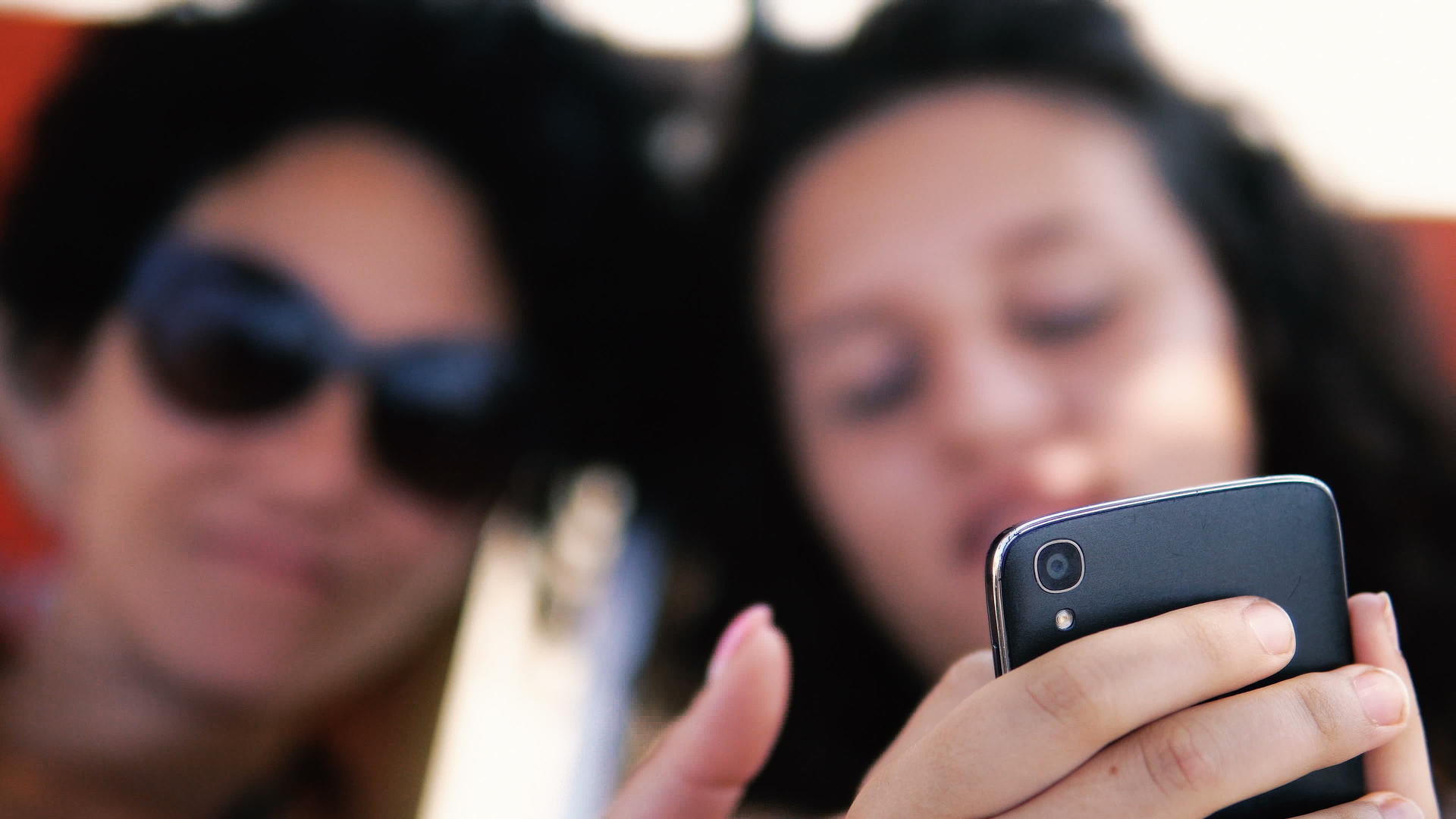 青少年在沙滩床上的智能手机上微笑着预览社交媒体帖子视频的预览图