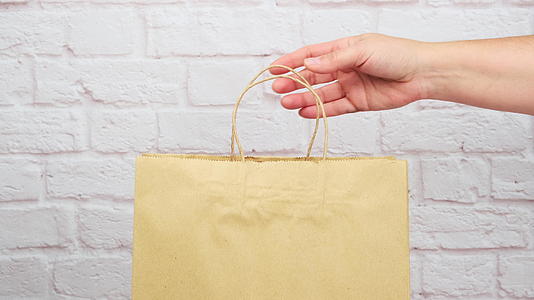 女性手里拿着棕色的纸袋放在购物和产品的把手上视频的预览图