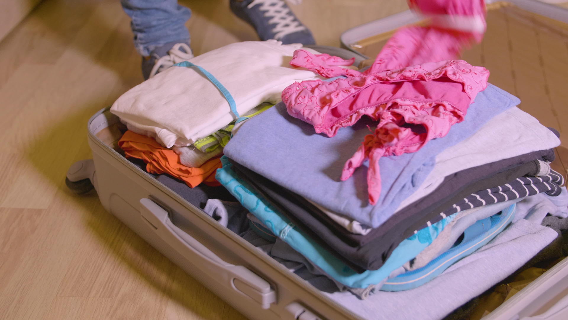 女人把东西和衣服放在旅行手提箱里放在家庭房间的地板上视频的预览图