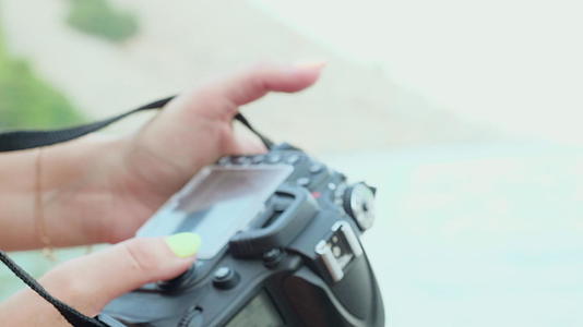 特写女摄影师用专业相机拍照女性在户外拍照时会看照片视频的预览图
