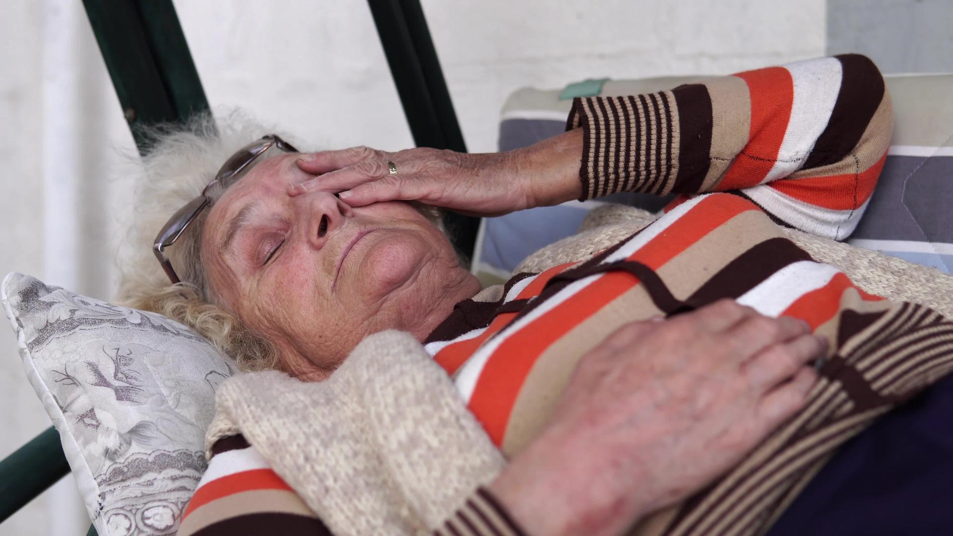 睡着的奶奶躺在门廊里在长凳上摇摆视频的预览图