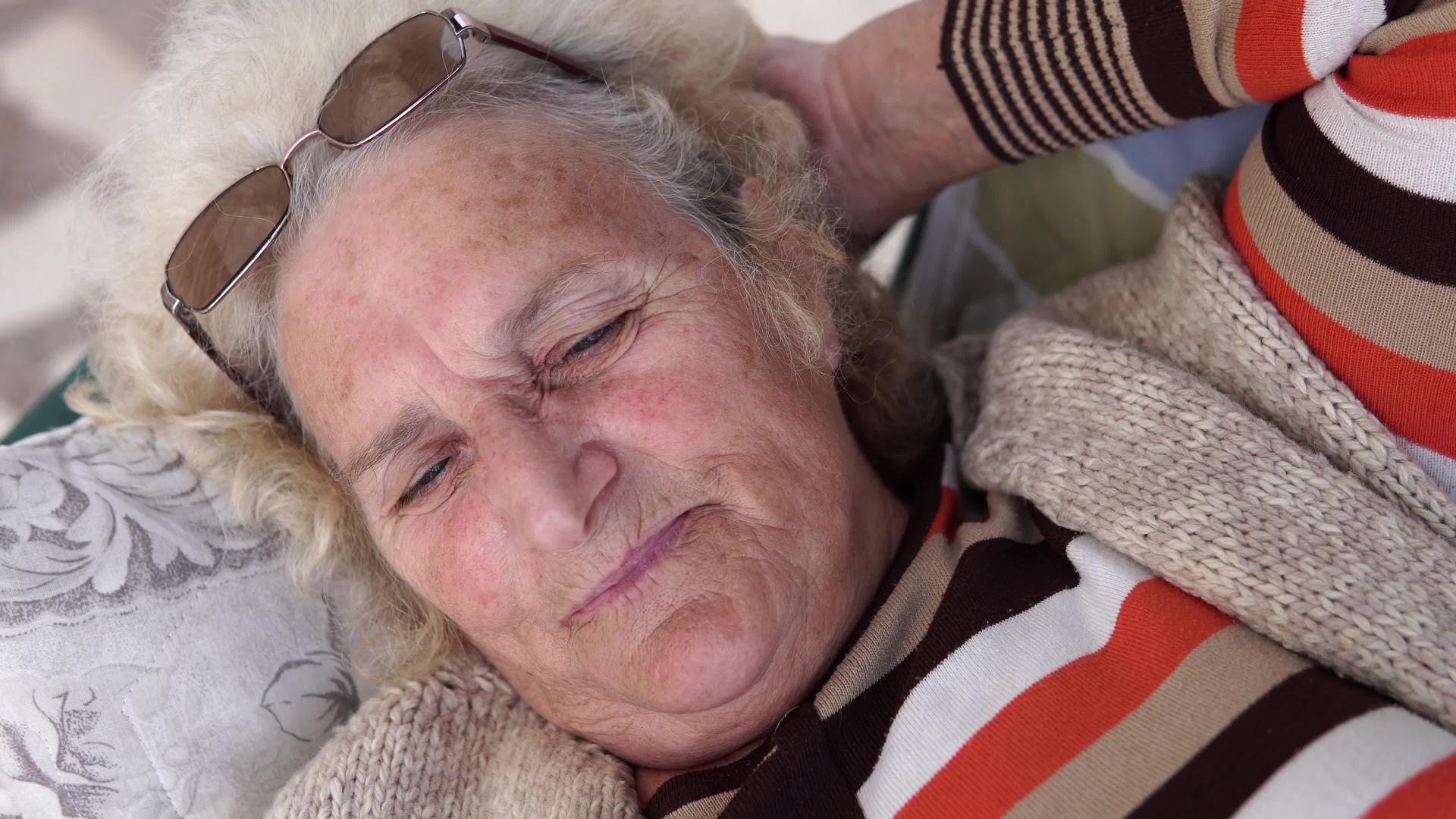 美丽的老年妇女肖像躺在户外门廊摇摆和思考视频的预览图