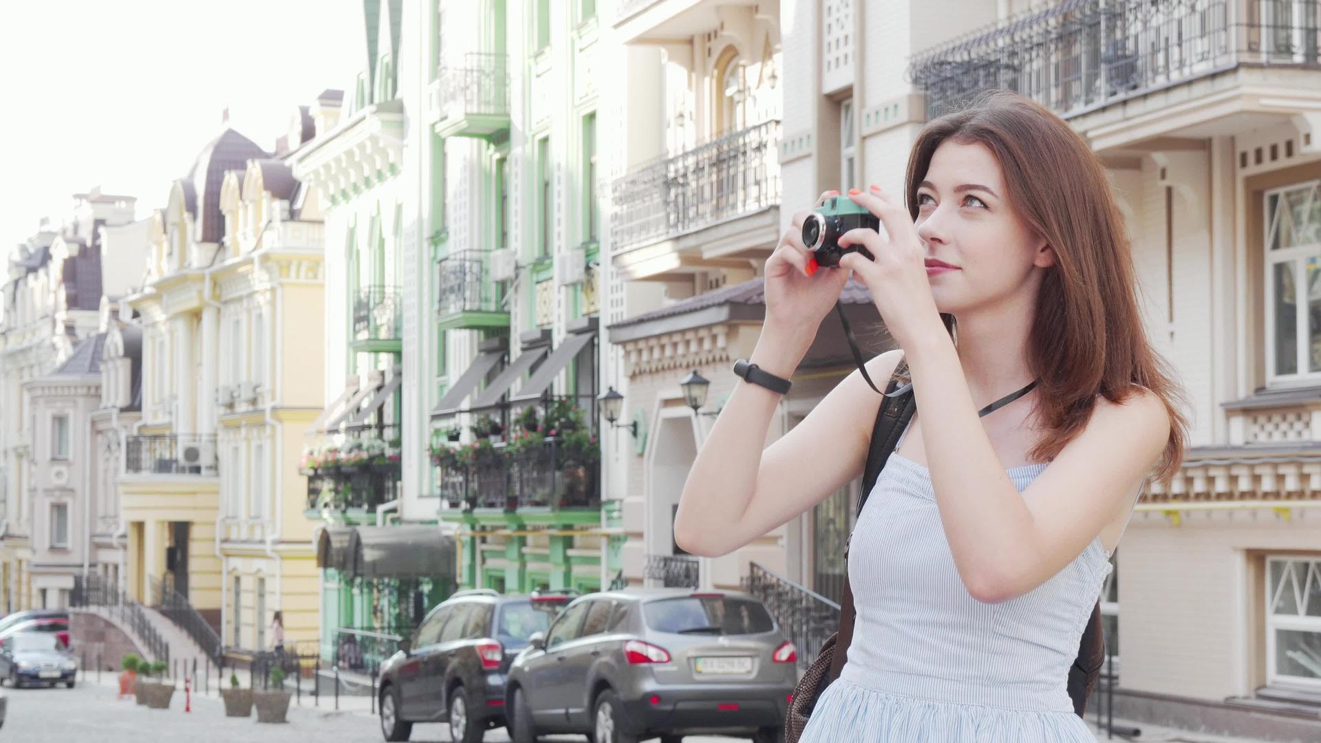 美丽的女人在她的反光相机上拍摄城市照片视频的预览图