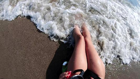 雌腿在浅海中飞溅海浪在岸上倾斜视频的预览图