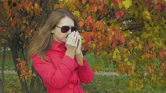 年轻的白人妇女戴着太阳镜和红色斗篷呆在树旁视频的预览图