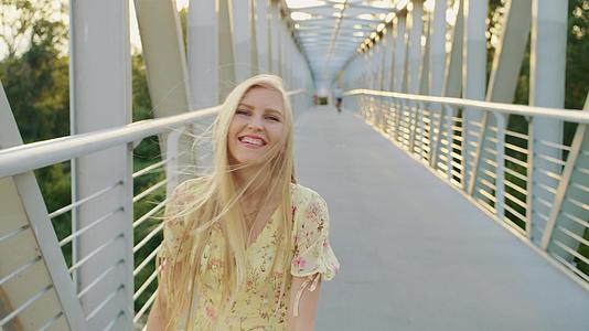 回首桥上的年轻女士美丽的金发女人在波浪形的桥上视频的预览图