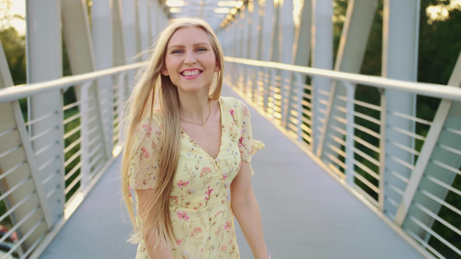 一个漂亮的金发女孩看着桥上的摄像机视频的预览图