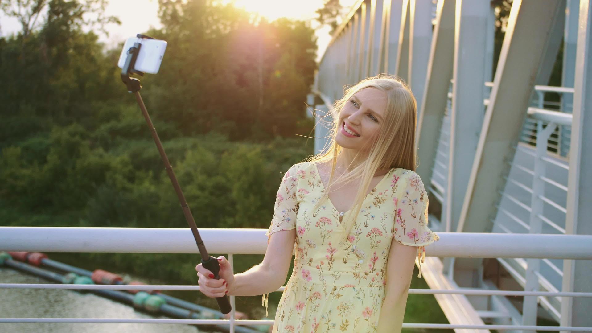快乐的金发美女站在行人桥上日落时与独角兽共舞视频的预览图