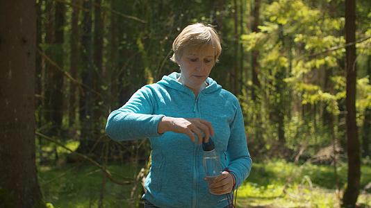 成熟的成年女性在森林中饮用水视频的预览图