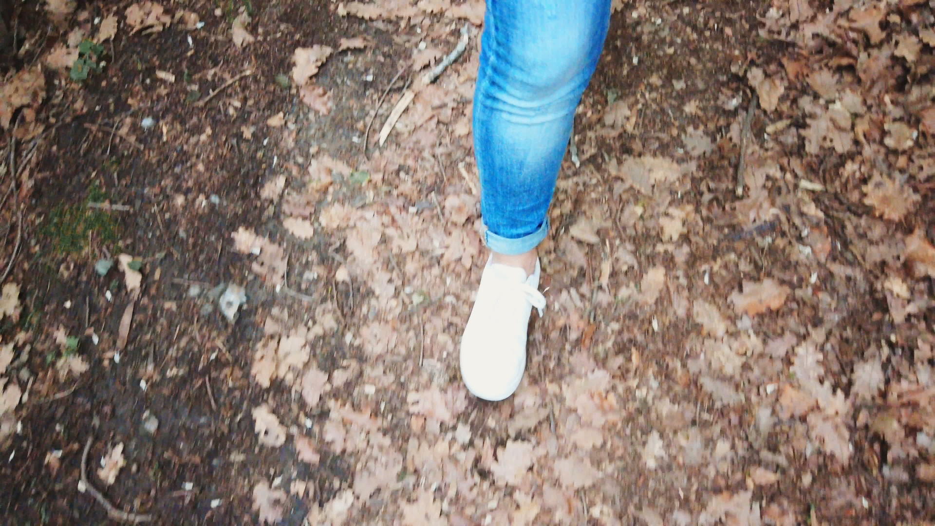 跟踪镜头穿着运动鞋和牛仔裤；走在森林里的女人视频的预览图